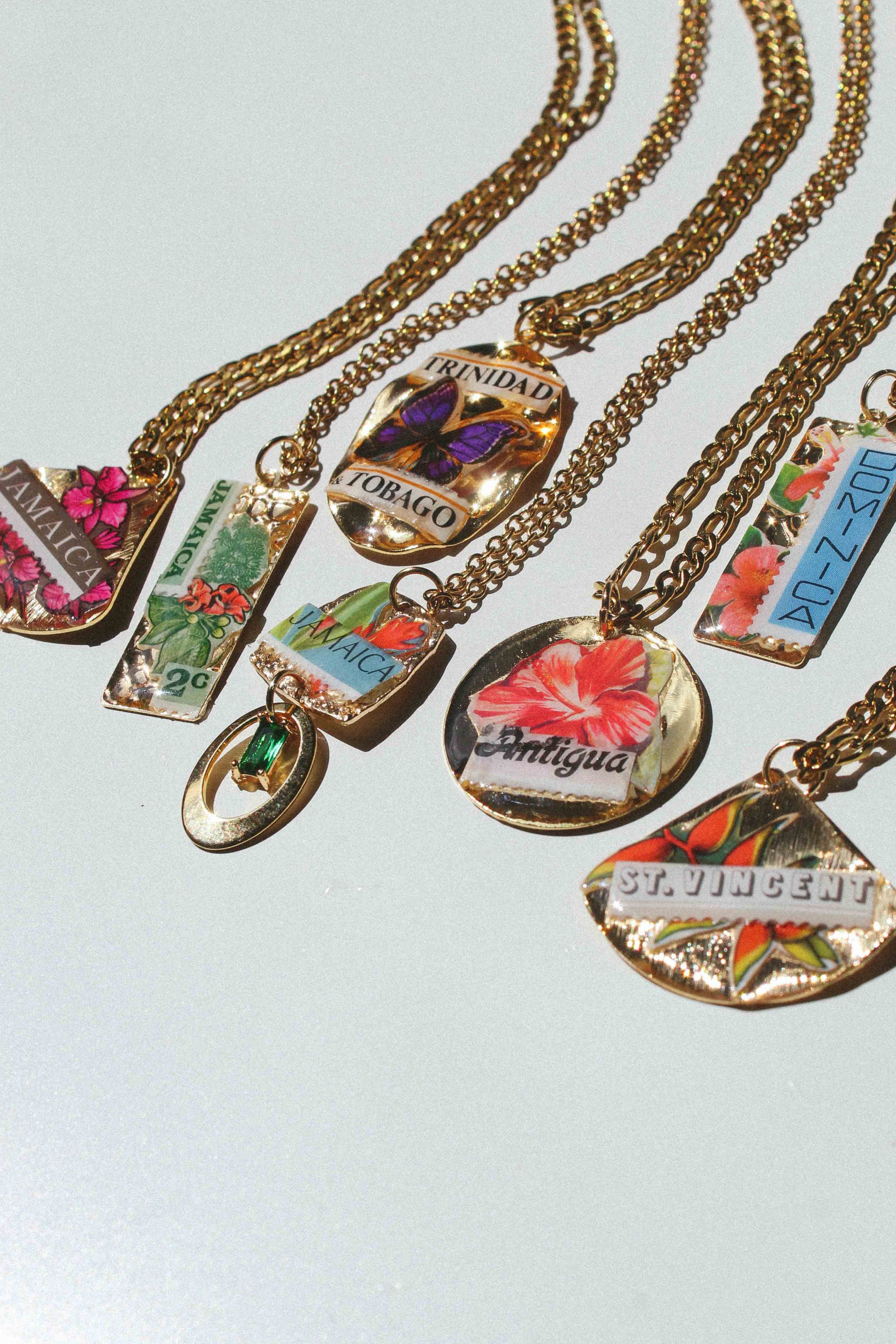 Gold Caribbean inspired necklaces with colorful pendants on a light gray background